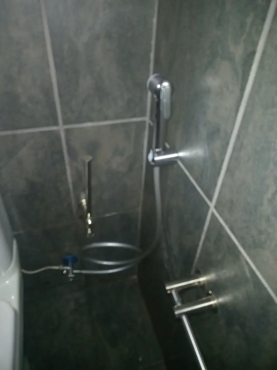 Dark tiled shower wall with chrome shower fixtures