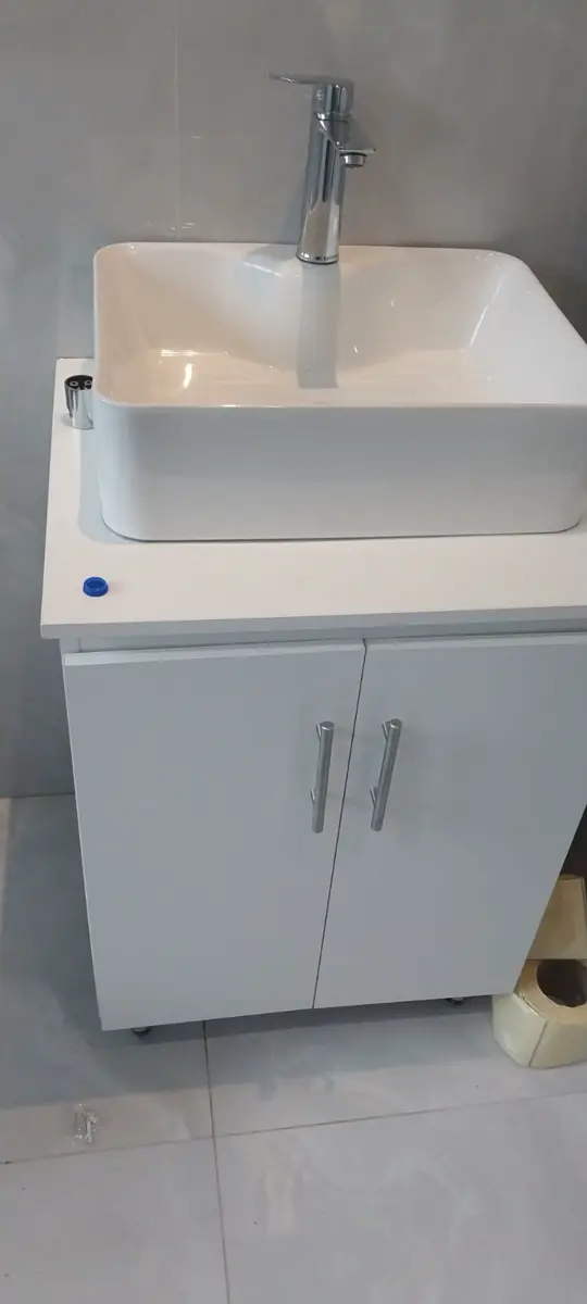 White bathroom vanity with a rectangular basin and chrome faucet